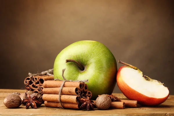 Bâtonnets de cannelle, pommes noix de muscade et anis sur table en bois sur fond brun — Photo