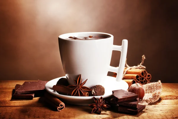 Tasse de chocolat chaud, bâtonnets de cannelle, noix et chocolat sur table en bois o — Photo
