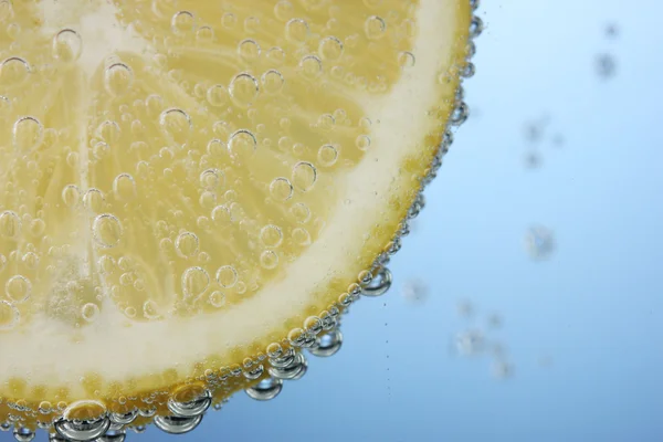 Fatia de limão na água azul com bolhas — Fotografia de Stock