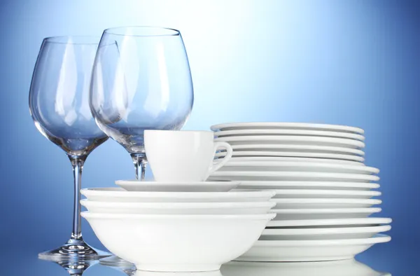 Leere Schalen, Teller, Tassen und Gläser auf blauem Hintergrund — Stockfoto