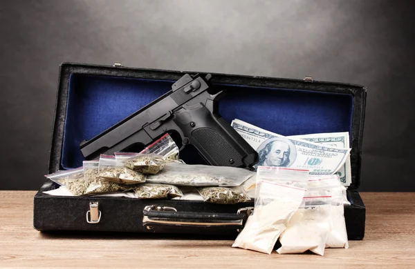 コカイン、マリファナ ドルおよび灰色の背面に木製のテーブルにケースで拳銃 — ストック写真