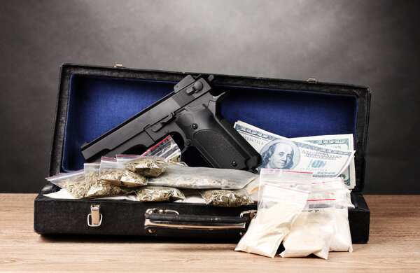 Кокаин, марихуана доллары и пистолет на случай, если на деревянном столе на серой спине
