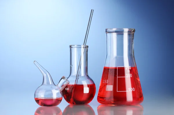 Three flasks with red liquid with reflection on blue background — Stock Photo, Image