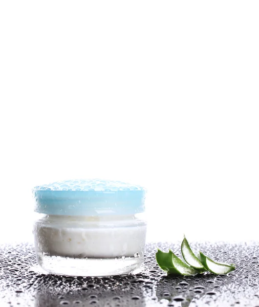 Closed glass jar of cream and aloe on black table with water droplets isola — Stock Photo, Image