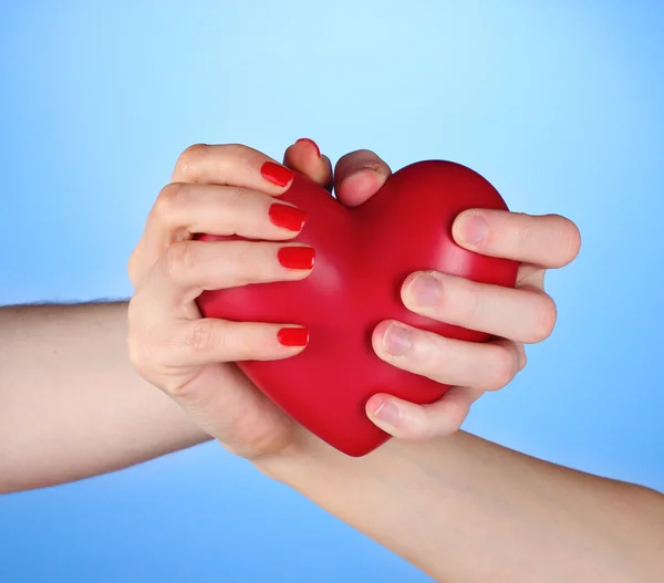 Man och kvinna med rött hjärta i händerna på blå bakgrund — Stockfoto