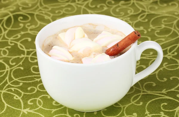 Xícara de cappucino com marshmallows e canela na toalha de mesa verde — Fotografia de Stock