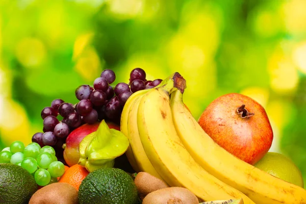 Assortiment van exotische vruchten op houten tafel op groene achtergrond — Stockfoto