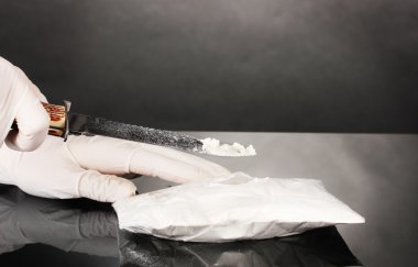 gri arka plan üzerine bir bıçakla açılırken bir kokain paketleri