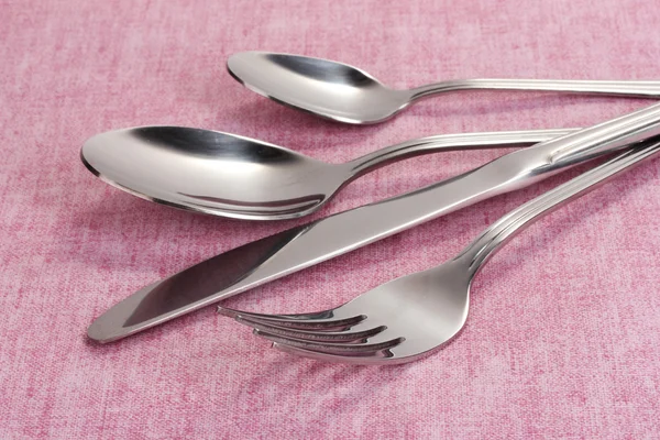 Vidlička, lžíce a nůž na růžové ubrus — Stock fotografie