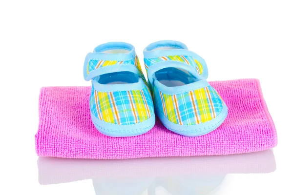 Botas de bebê azul na toalha rosa isolada no branco — Fotografia de Stock