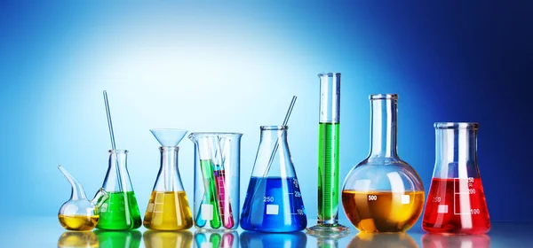 Verschillende laboratoriumglaswerk met kleur vloeistof en reflectie op blu — Stockfoto