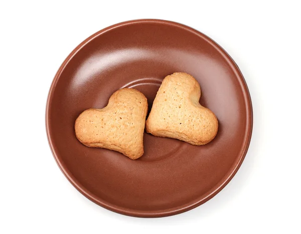 Due biscotti a forma di cuore su piattino marrone isolato su bianco — Foto Stock