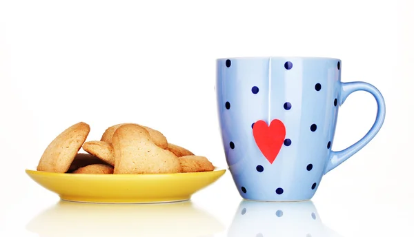 Tazza blu con bustina di tè e biscotti a forma di cuore su piatto giallo isolato su — Foto Stock