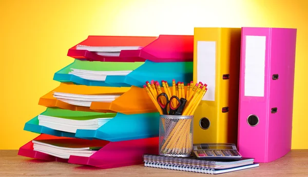 Helle Papiertabletts und Schreibwaren auf Holztisch auf gelbem Hintergrund — Stockfoto