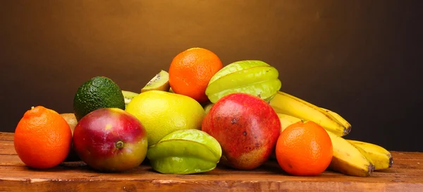 stock image Assortment of exotic fruits on wooden table on brown background