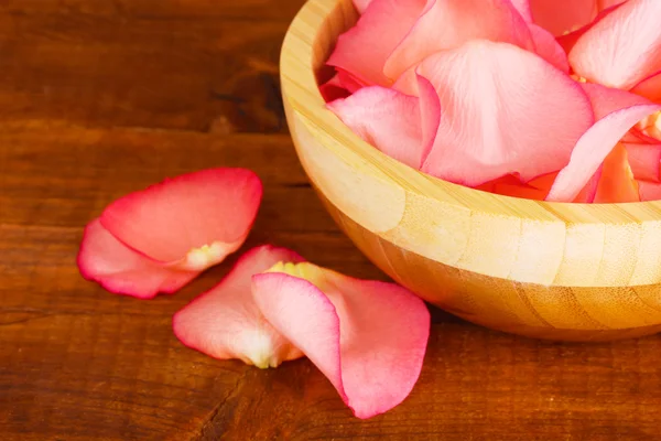 Beautiful pink rose petals in wooden bowl on table — Stock Photo, Image