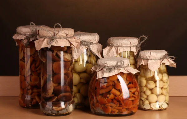 Deliciosos champiñones marinados en los frascos de vidrio en el estante de madera —  Fotos de Stock