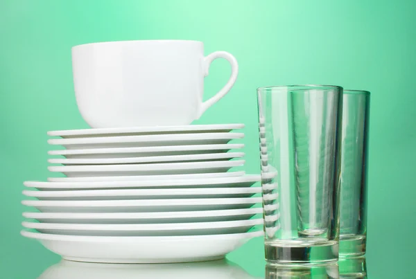 Platos limpios, taza y vasos sobre fondo verde —  Fotos de Stock