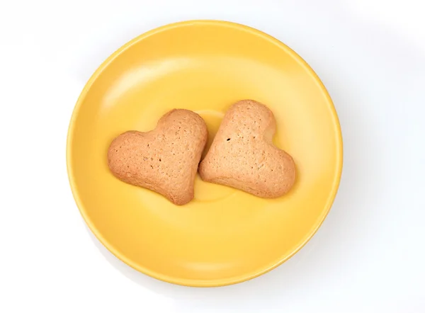 Two heart-shaped cookies on yellow saucer isolated on white — Stock Photo, Image
