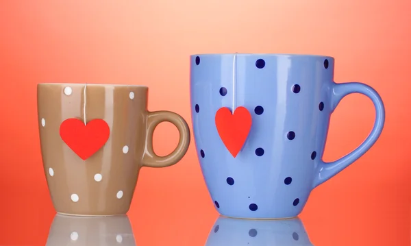 Dva šálky a čajové sáčky s červeným štítkem ve tvaru srdce na červeném pozadí — Stock fotografie