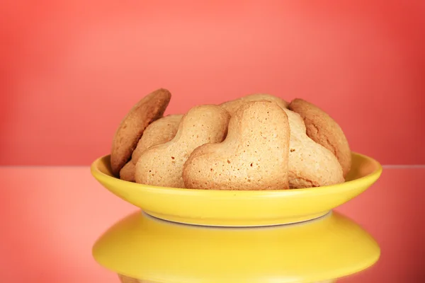 Herzförmige Kekse auf gelbem Teller auf rotem Hintergrund — Stockfoto