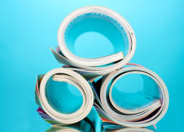 Rolled up magazines on blue background clipart