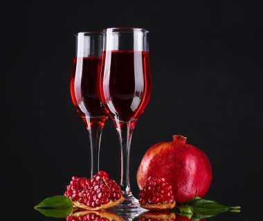 Ripe pomergranate and glasses of wine on black background clipart