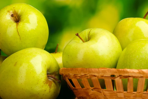 Сочные зеленые яблоки в корзине на зеленом фоне — стоковое фото
