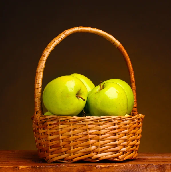 Soczyste zielone jabłka kosz na drewnianym stole na brązowym tle — Zdjęcie stockowe