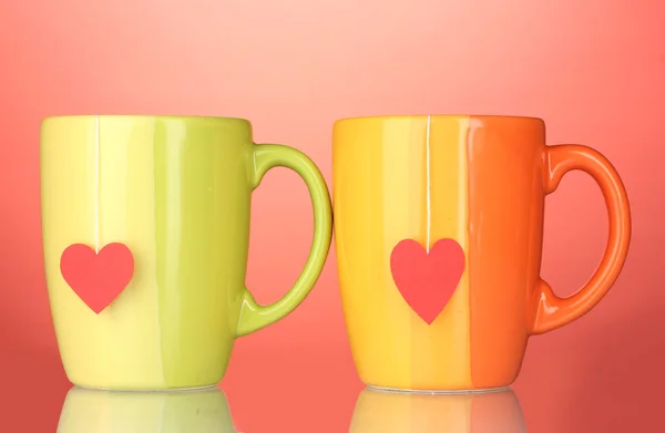 Two cups and tea bags with red heart-shaped label on red background — Stock Photo, Image