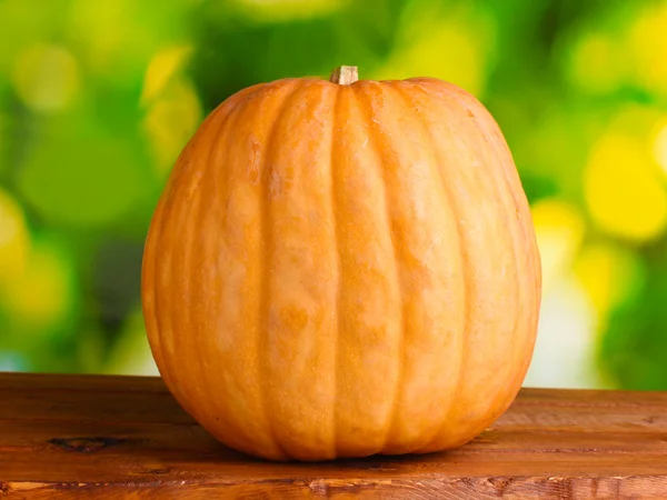 Pumpkin on wooden table on green background — Stock Photo, Image