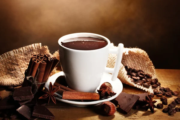 Cup of hot chocolate, cinnamon sticks, nuts and chocolate on wooden table o Stock Photo