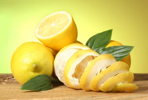 Zralých citronů s listy na dřevěný stůl na zeleném pozadí — Stock fotografie