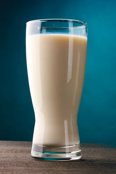 Vidro de leite na mesa de madeira no fundo azul — Fotografia de Stock