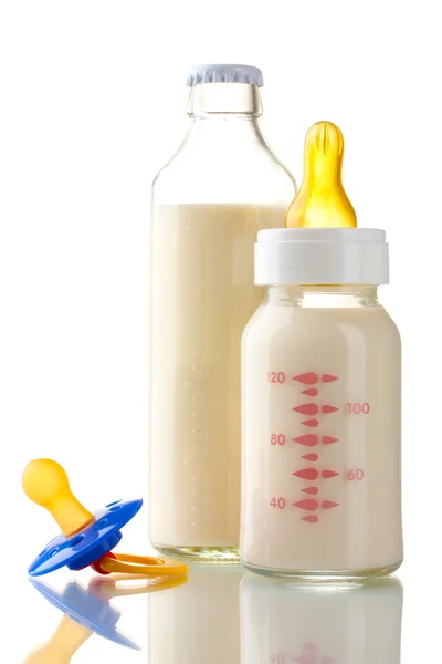 Bottles of milk and soother isolated on white — Stockfoto