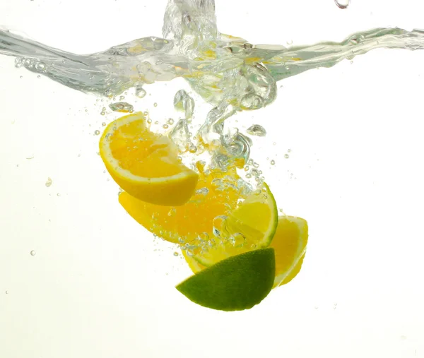 Segmenten van citroen en kalk in het water — Stockfoto