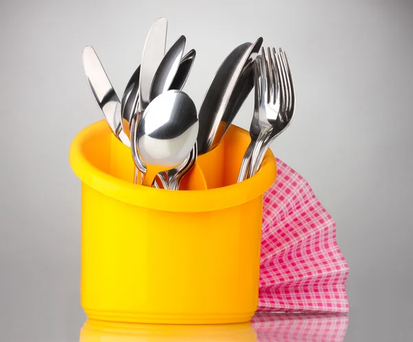 Kitchen cutlery, knives, forks and spoons in yellow stand with pink napkin — Stock Photo, Image