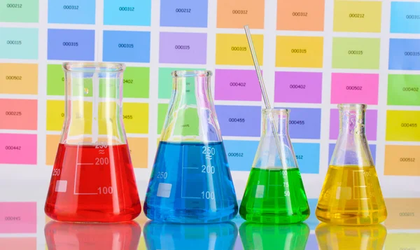 Frascos de laboratório com líquido de cor em fundo de amostras de cor — Fotografia de Stock