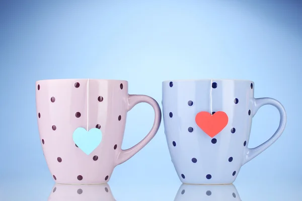 Duas xícaras e sacos de chá com rótulo vermelho e azul em forma de coração no backgrou azul — Fotografia de Stock