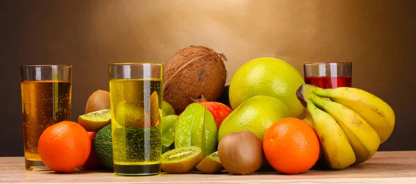 Sortiment an exotischen Früchten und Saft auf Holztisch auf braunem Hintergrund — Stockfoto