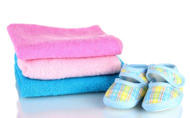 Blue baby booties and three colorful towels isolated on white