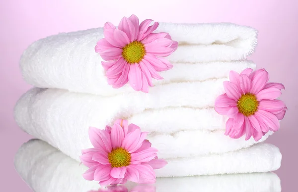 Pyyhkeet ja kauniit kukat vaaleanpunaisella taustalla — kuvapankkivalokuva