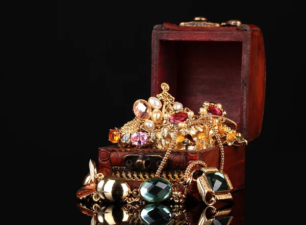 Trä bröst full av guld smycken på svart bakgrund — Stockfoto