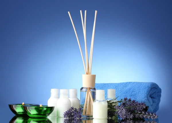 Fles luchtverfrisser, lavendel, handdoek en kaarsen op blauwe achtergrond — Stockfoto
