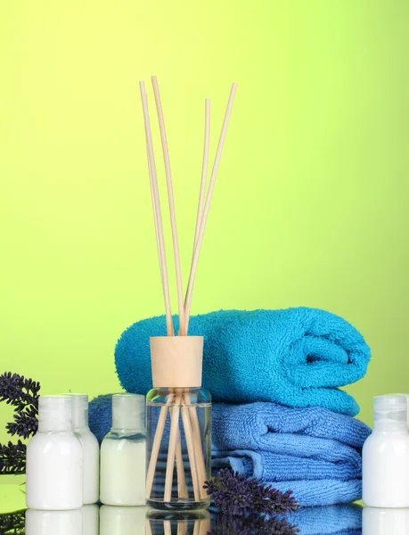 Osvěžovač vzduchu, travarica a ručníky na zeleném pozadí — Stock fotografie
