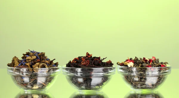 Различные виды зеленого и черного сухого чая на зеленом фоне — стоковое фото