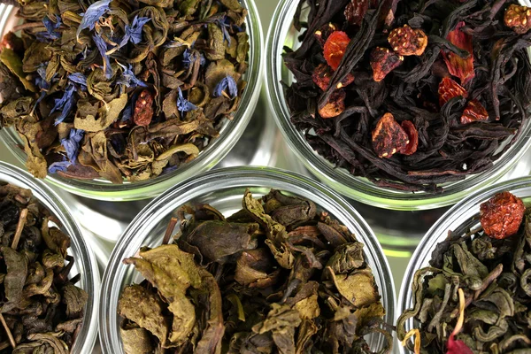 Sammlung von grünem und schwarzem trockenen Tee in Tellern auf grünem Grund — Stockfoto