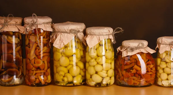 Deliciosos champiñones marinados en los frascos de vidrio en el estante de madera — Foto de Stock