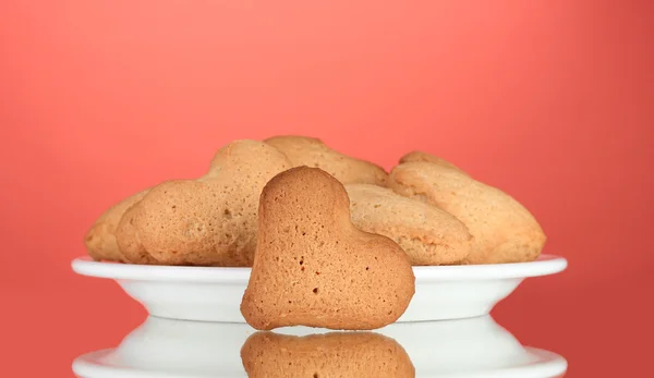 Cookies em forma de coração na placa no fundo vermelho — Fotografia de Stock