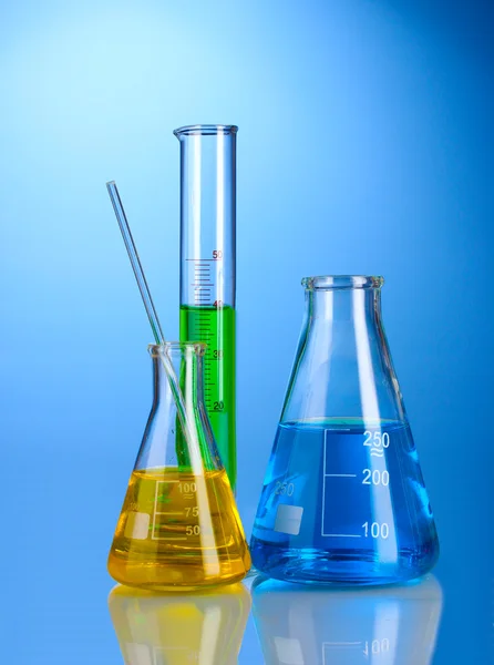 Tres frascos con líquido de color con reflexión sobre fondo azul —  Fotos de Stock